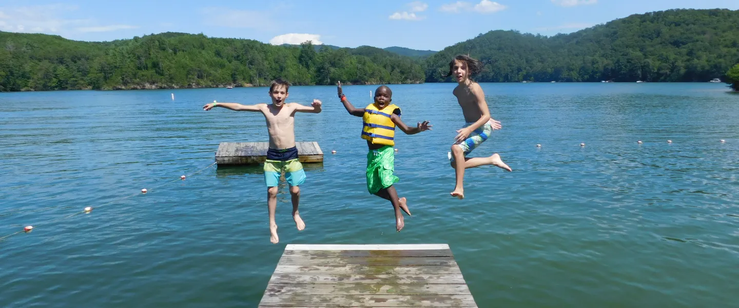 three boys jumping into the lake